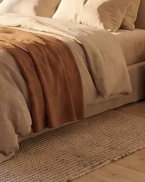 Detalle: ropa de cama de lino y una alfombra de yute, imagen generada con IA